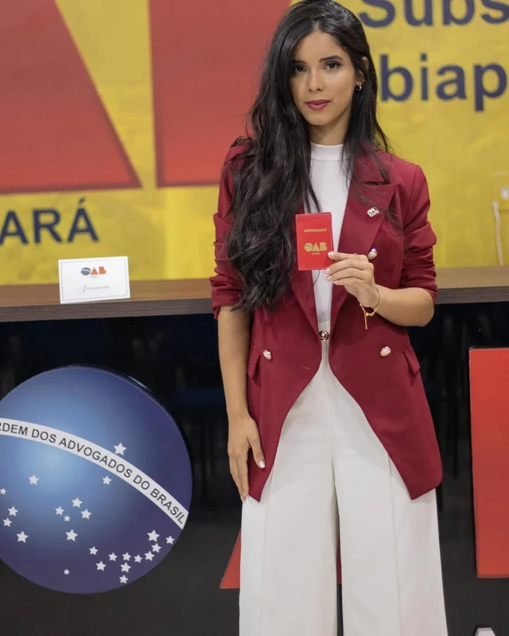 Vanessa Britto com sua carteira da OAB, vestindo um blazer vinho